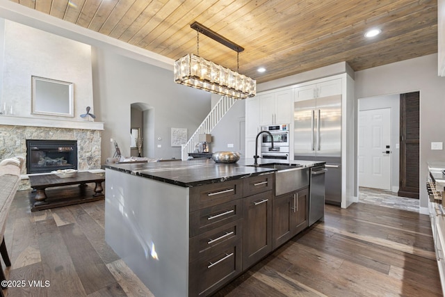 kitchen featuring dark wood finished floors, a fireplace, white cabinets, dark stone countertops, and wooden ceiling