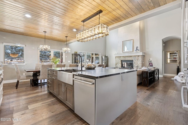 kitchen featuring dark wood-style flooring, a fireplace, a notable chandelier, a sink, and dishwasher