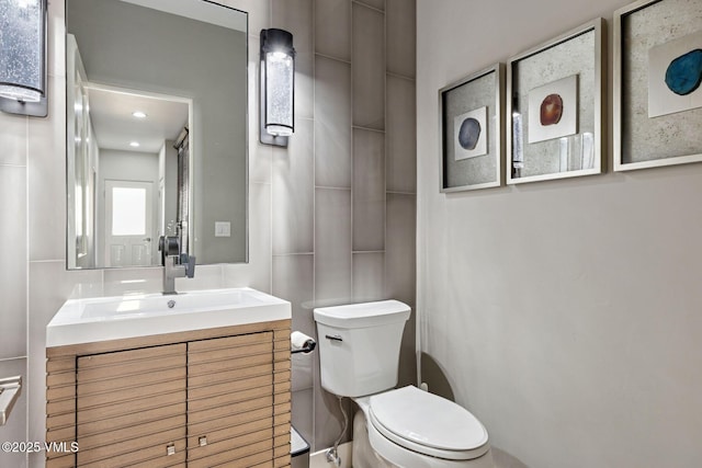 bathroom featuring decorative backsplash, tile walls, toilet, and vanity