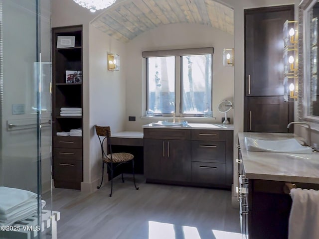 bathroom with lofted ceiling, wood finished floors, a sink, two vanities, and a shower stall