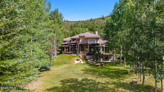 266 Sawatch Dr, Edwards, CO 81632 - back of property with a pergola, a forest view, a patio area, a lawn, and a chimney
