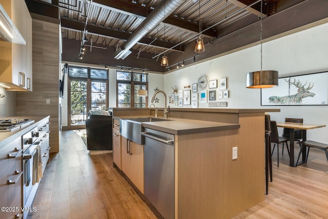 37347 US Highway 6 Unit 101, Avon, CO 81620 - kitchen with stainless steel dishwasher, light wood-style floors, a sink, a kitchen island with sink, and hanging light fixtures