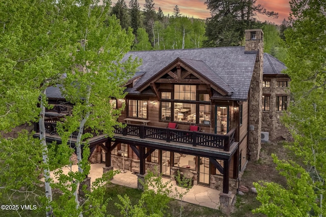 348 Red Draw, Edwards, CO 81632 - rear view of property with stone siding, a wooden deck, a patio area, and a chimney