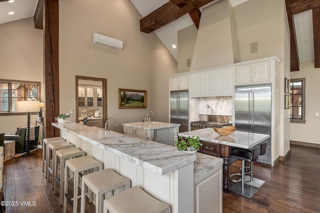 348 Red Draw, Edwards, CO 81632 - kitchen with an island with sink, stainless steel built in fridge, a wall mounted AC, high vaulted ceiling, and beam ceiling