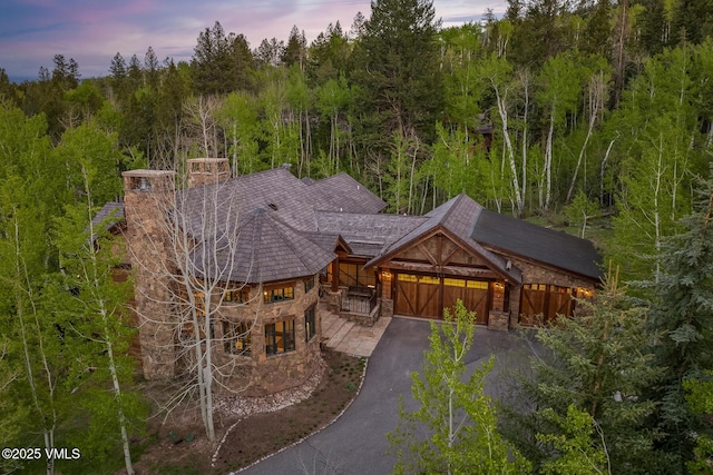 348 Red Draw, Edwards, CO 81632 - view of front of home with stone siding, asphalt driveway, a garage, and a chimney