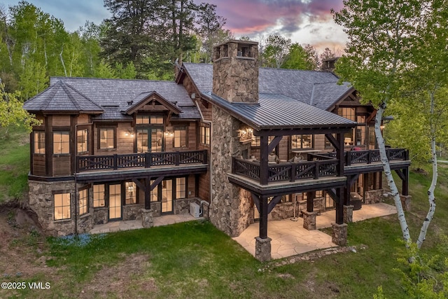 348 Red Draw, Edwards, CO 81632 - back of house at dusk with a patio area, a standing seam roof, and stone siding