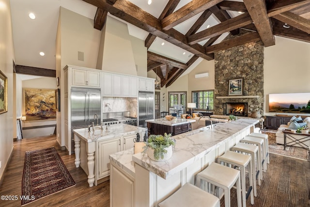 348 Red Draw, Edwards, CO 81632 - kitchen with a large island, stainless steel built in fridge, a stone fireplace, beamed ceiling, and high vaulted ceiling