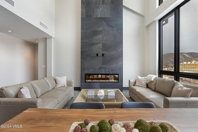 living room featuring a tiled fireplace and a high ceiling