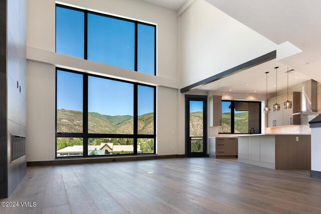 unfurnished living room featuring a high ceiling, a mountain view, and dark wood-type flooring