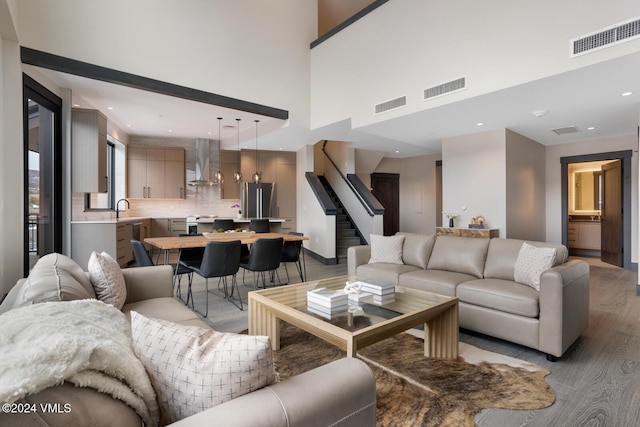 living room featuring sink, light hardwood / wood-style flooring, and a high ceiling