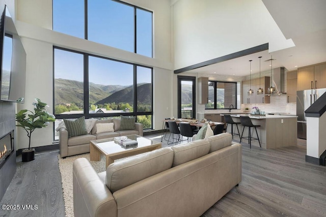 42 Riverfront Ln Unit 507, Avon, CO 81620 - living area featuring a high ceiling, light wood-style flooring, a mountain view, and a tiled fireplace