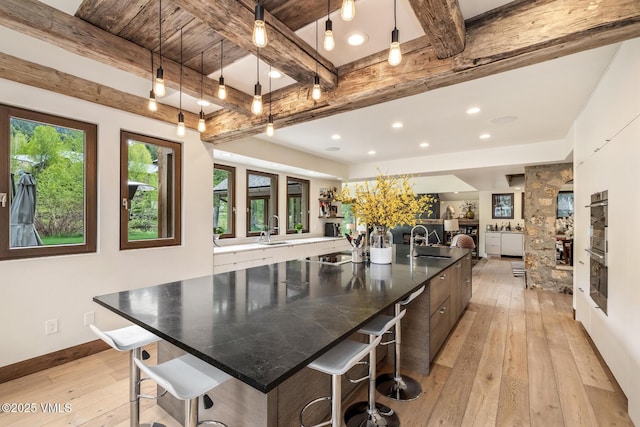89 Trout Pond Ln, Avon, CO 81620 - kitchen with light wood-type flooring, beam ceiling, a kitchen breakfast bar, a spacious island, and pendant lighting