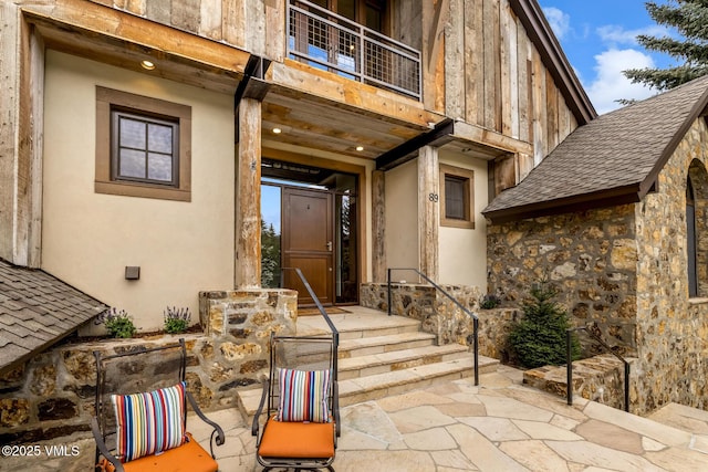 89 Trout Pond Ln, Avon, CO 81620 - view of exterior entry with stone siding, a balcony, and stucco siding
