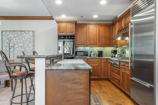 62 Highlands Ln Unit R103, R102, Beaver Creek, CO 81620 - kitchen with stainless steel appliances, crown molding, range hood, dark stone countertops, and a kitchen bar