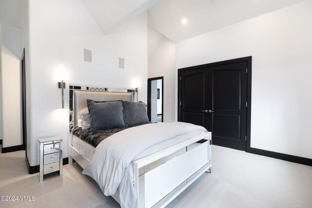 carpeted bedroom with high vaulted ceiling