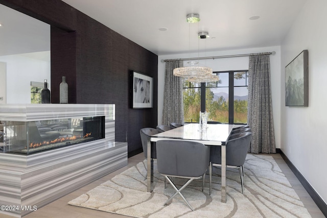 dining space featuring a multi sided fireplace and light hardwood / wood-style flooring