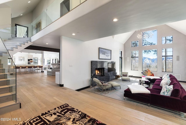 living room with a fireplace, high vaulted ceiling, and light hardwood / wood-style flooring