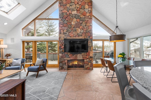 living area featuring high vaulted ceiling, a skylight, recessed lighting, a stone fireplace, and stone finish floor