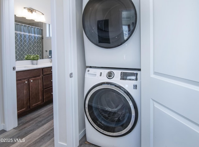 laundry room with wood finished floors, stacked washer and clothes dryer, and laundry area