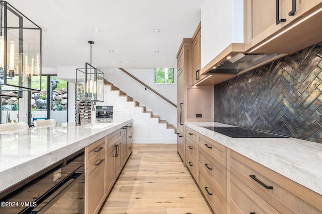 kitchen with sink, tasteful backsplash, decorative light fixtures, black electric cooktop, and light stone countertops