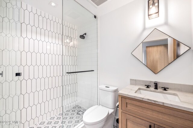 bathroom featuring vanity, toilet, and tiled shower