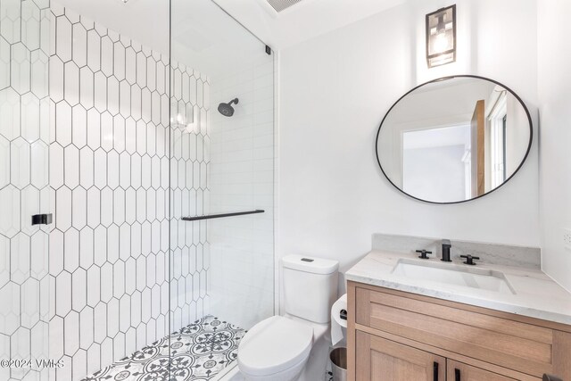 bathroom featuring vanity, toilet, and tiled shower