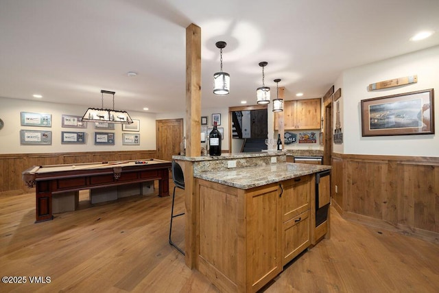 775 Potato Patch Dr Unit E, Vail, CO 81657 - kitchen featuring a wainscoted wall, light wood-style floors, recessed lighting, light stone countertops, and hanging light fixtures