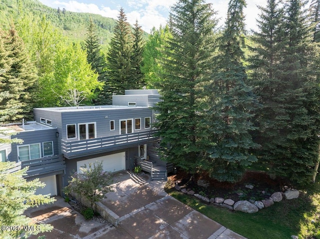 775 Potato Patch Dr Unit E, Vail, CO 81657 - view of front facade featuring an attached garage, a forest view, concrete driveway, and a balcony