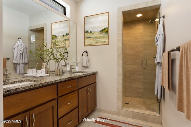 full bathroom with a sink, a shower stall, and double vanity