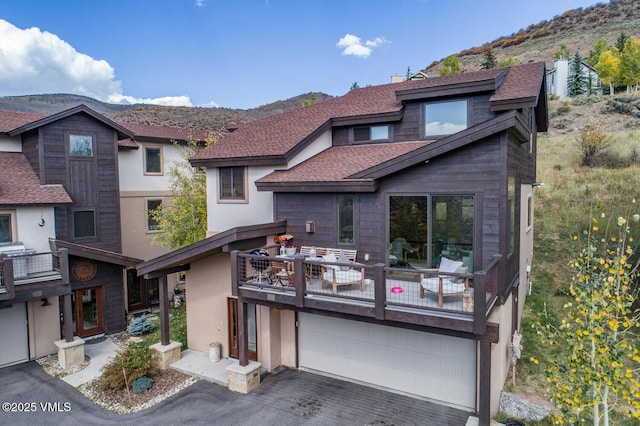 view of front of property featuring roof with shingles, driveway, a balcony, and a mountain view