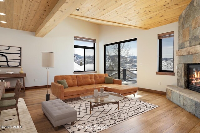 living room featuring a large fireplace, light wood finished floors, lofted ceiling with beams, wooden ceiling, and a mountain view