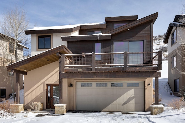 contemporary house featuring an attached garage, a balcony, and stucco siding