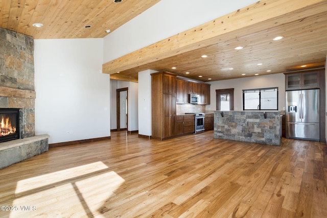 unfurnished living room with baseboards, wood ceiling, a stone fireplace, light wood-type flooring, and recessed lighting