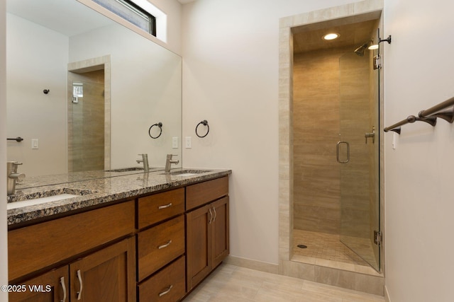 bathroom with a stall shower, a sink, and double vanity