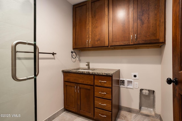 washroom featuring cabinet space, baseboards, a sink, hookup for a washing machine, and electric dryer hookup