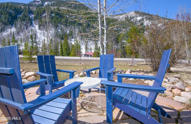 wooden deck featuring a wooded view, a mountain view, and a patio area
