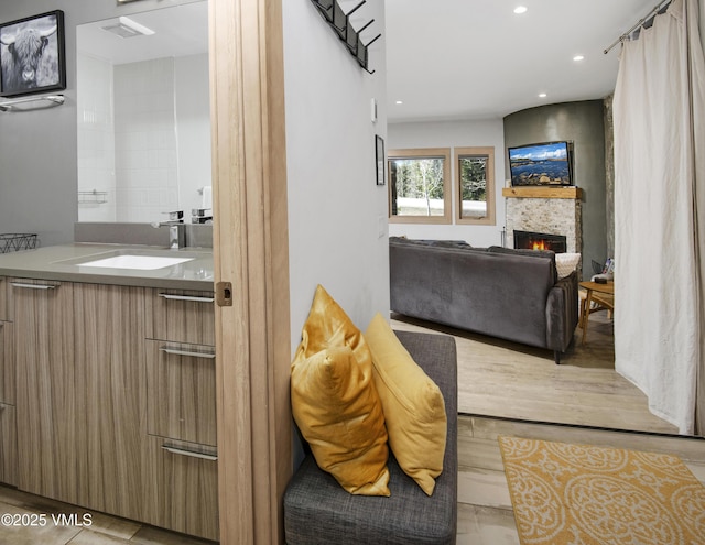 interior space with recessed lighting, wood finished floors, vanity, and a fireplace