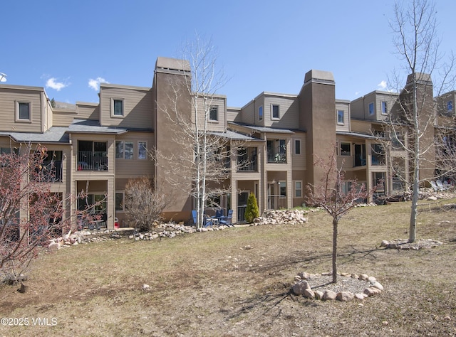 back of property featuring a chimney and a balcony