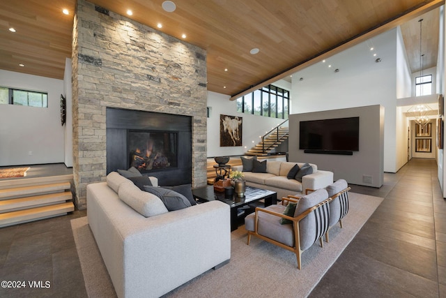 living room featuring a notable chandelier, a towering ceiling, wooden ceiling, and a fireplace