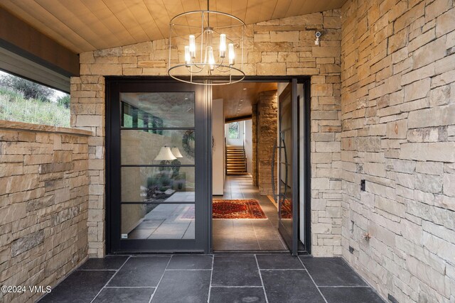 doorway to outside with vaulted ceiling, wood ceiling, and an inviting chandelier