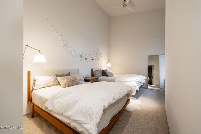 carpeted bedroom featuring ceiling fan and a towering ceiling