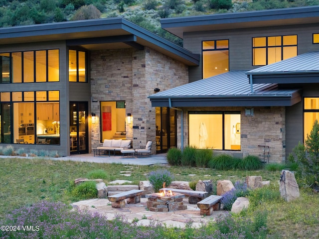 rear view of house with a patio and an outdoor living space with a fire pit