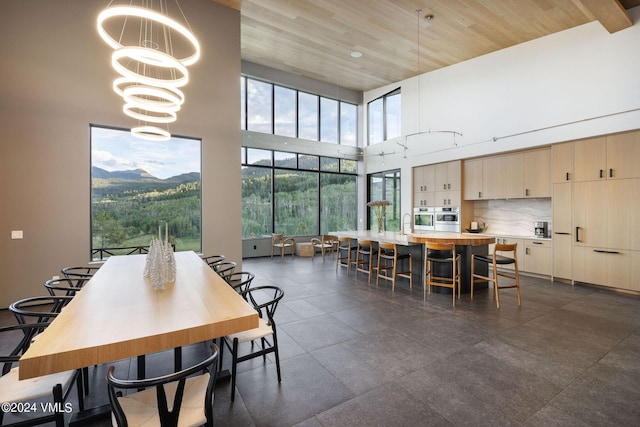 dining space featuring sink, wood ceiling, a high ceiling, a mountain view, and a chandelier