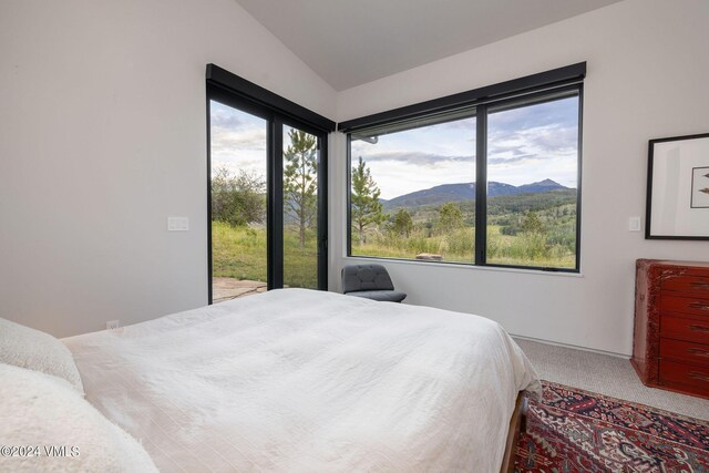 carpeted bedroom featuring lofted ceiling and a mountain view