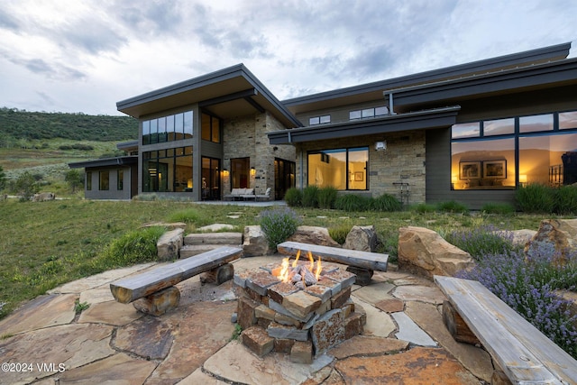 rear view of property featuring a patio and a fire pit