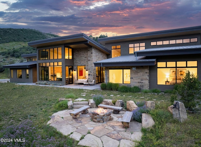 back house at dusk featuring a yard and a patio area