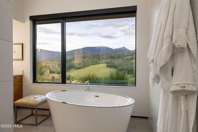 bathroom featuring vanity, a mountain view, tile patterned floors, and a bath