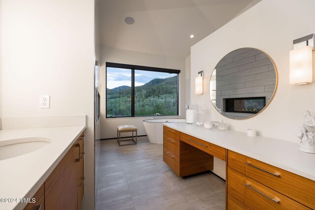 bathroom featuring a tub to relax in, vanity, a fireplace, and vaulted ceiling