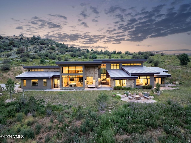 back house at dusk featuring an outdoor fire pit and a patio area