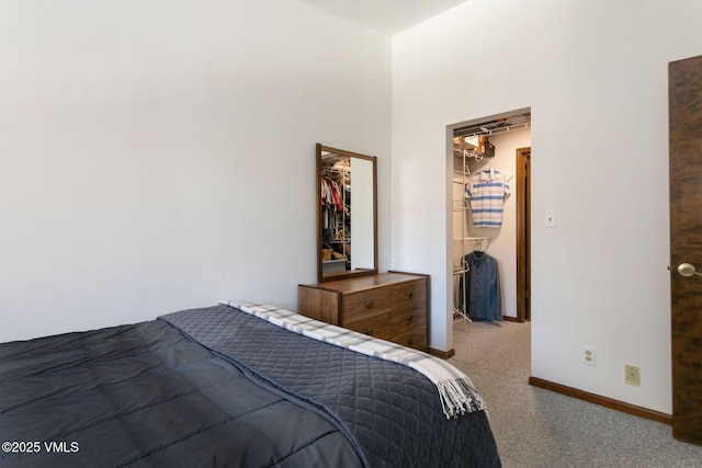 carpeted bedroom featuring a closet, a spacious closet, and baseboards